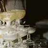 Champagne being poured into a pyramid of coupe glasses, overflowing and creating a celebratory cascade.